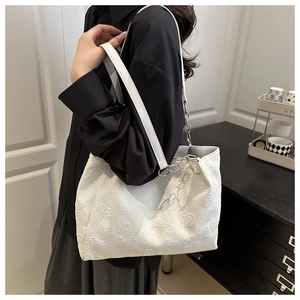 Detail of white tote bag featuring heart embroidery and silver metal chain strap