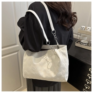 Detail of white tote bag featuring 3D heart embossing and silver chain metal hardware