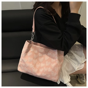 Close-up of pink tote bag with white heart jacquard pattern and metal ring strap detail
