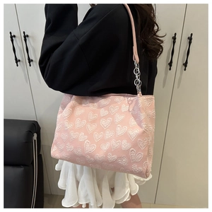 Detailed texture of pink tote bag with white heart embroidery and silver chain strap