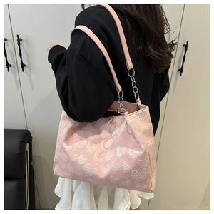 Detail of pink tote bag with white 3D heart patterns and elegant metal chain strap