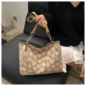 Detail of beige tote bag with white heart embroidery and leather-chain shoulder strap