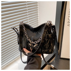 Close-up of black pleated bag featuring a silver chain and metal butterfly buckle