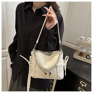 Détail du sac crème avec breloques papillon en argent et plis délicats en cuir