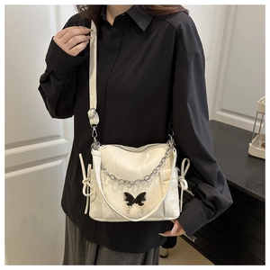 Detail of white glossy leather shoulder bag with black butterfly metal ornament and bow