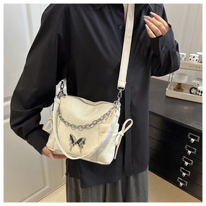 Détail du sac crème à chaîne avec décor papillon métallique et finitions argentées