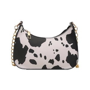Chic black and white cow print half-moon underarm bag with elegant gold chain strap