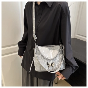 Détail du sac bandoulière argenté plissé avec boucle papillon et chaîne en métal