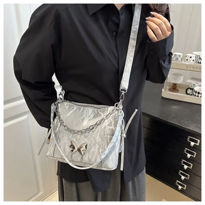 Détail du sac argenté froissé avec boucle papillon métallique et bandoulière en chaîne