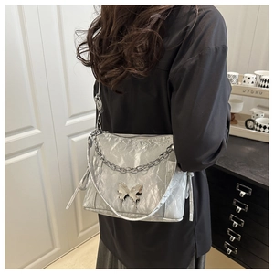 Détail du sac à bandoulière plissé argenté avec boucle papillon et chaîne en métal