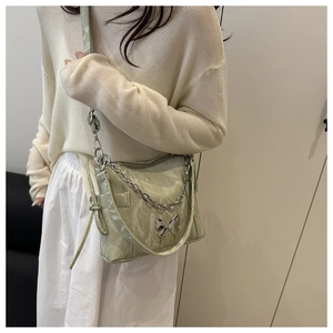 Detail of light green ruched crossbody bag with silver butterfly and chain strap