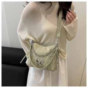 Détail du sac bandoulière vert pistache en cuir ciré plissé avec papillon argenté