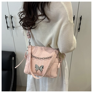 Vue détaillée du sac rose avec pendentif papillon argenté et détail de bandoulière
