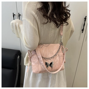 Détail d'un sac plissé rose clair avec boucle papillon métallique et chaîne argentée