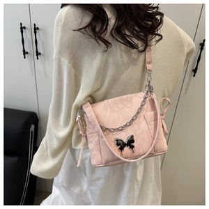 Détail du sac à bandoulière rose clair avec boucle papillon et cuir plissé élégant