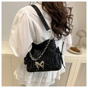 Detail of black leather shoulder bag with silver butterfly buckle and chunky chain strap