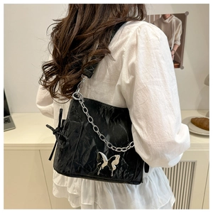 Détail du sac à bandoulière noir plissé avec boucle papillon argentée et chaîne épaisse
