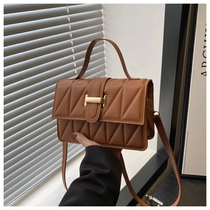 Détail du sac bandoulière en cuir matelassé marron avec fermoir doré et poignée