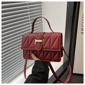 Détail du sac matelassé bordeaux avec boucle en H dorée et coutures élégantes