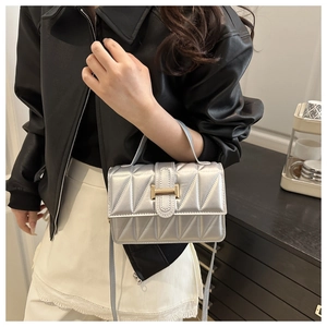 Détail d'un sac bandoulière argenté matelassé avec boucle en métal doré