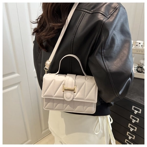 Détail du sac à bandoulière matelassé beige avec boucle dorée et sangle sur le mannequin