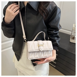 Détail d'un sac à bandoulière beige matelassé avec boucle en métal doré et bandoulière