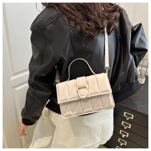 Détail du petit sac carré ivoire avec fermoir doré et poignée porté par un mannequin