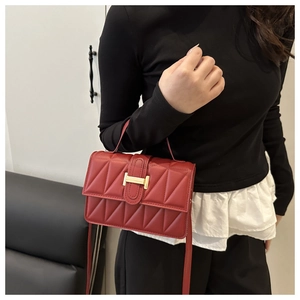 Détail du sac rouge matelassé avec un fermoir doré en forme de H et une texture élégante