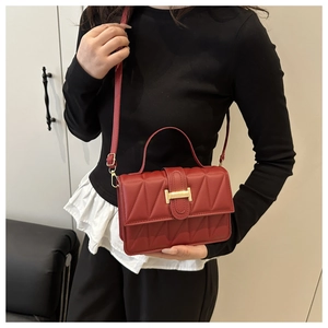Détail d'un sac à main matelassé rouge avec fermoir doré en H et texture en cuir PU