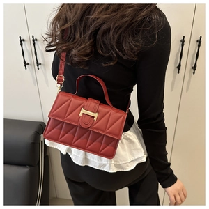 Détail du sac à bandoulière matelassé rouge avec boucle H dorée porté par un mannequin