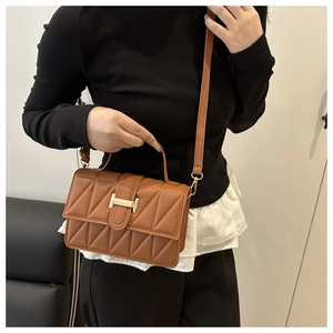Détail d'un sac à main matelassé marron caramel avec boucle H dorée sur un mannequin