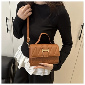 Détail du sac matelassé marron avec boucle en T dorée et poignée supérieure élégante