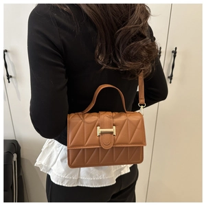 Sac bandoulière marron matelassé avec fermoir H doré porté par un mannequin