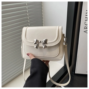Close-up of cream leather shoulder bag with a silver metal bow clasp detail