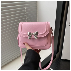 Detail of pink PU leather crossbody bag featuring a delicate silver metal bow accessory