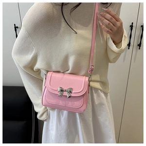 Detailed close-up of pink crossbody bag with a metal bow accent and silver hardware