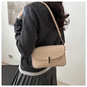 Detail of beige faux crocodile leather shoulder bag with elegant gold metal twist lock