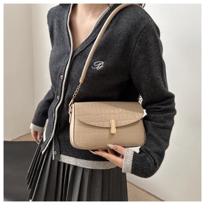 Detail view of beige crocodile embossed leather bag with gold buckle and chain strap