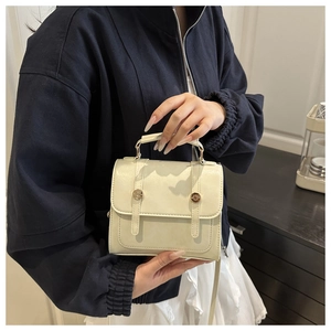Dettaglio della borsa a tracolla in pelle PU crema con fibbie dorate e cinturini decorativi