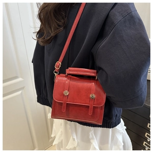 Dettaglio di una borsa a tracolla rossa vintage con fibbie dorate e manico superiore