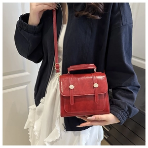 Gros plan du sac vintage en cuir rouge vif avec boucle sur un manteau bleu marine