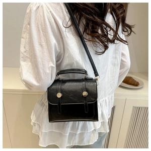 Détail d'un sac à dos noir vintage avec rivets dorés et poignée supérieure sur fond blanc