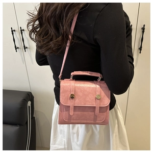 Détails du petit sac carré rose rétro avec lanières décoratives et boucles dorées sur modèle