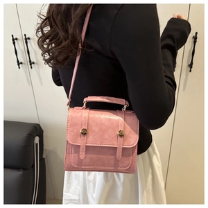 Gros plan d'un sac à bandoulière en similicuir rose avec boucles en métal doré