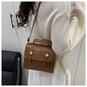 Détail d'un sac à main rétro marron avec doubles brides et boucles dorées élégantes