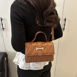 Petit sac bandoulière matelassé marron avec boucle dorée en H porté par mannequin