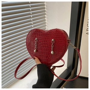 Detailed close-up of red heart bag with crocodile texture and silver chain charms