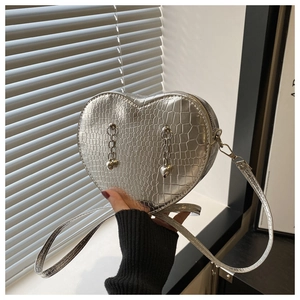 Detail of silver heart-shaped crossbody bag with crocodile texture and metal chains