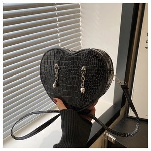 Detail of black heart-shaped shoulder bag featuring crocodile texture and silver chains