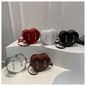 Macro view of heart-shaped bags in crocodile embossed leather with silver chains